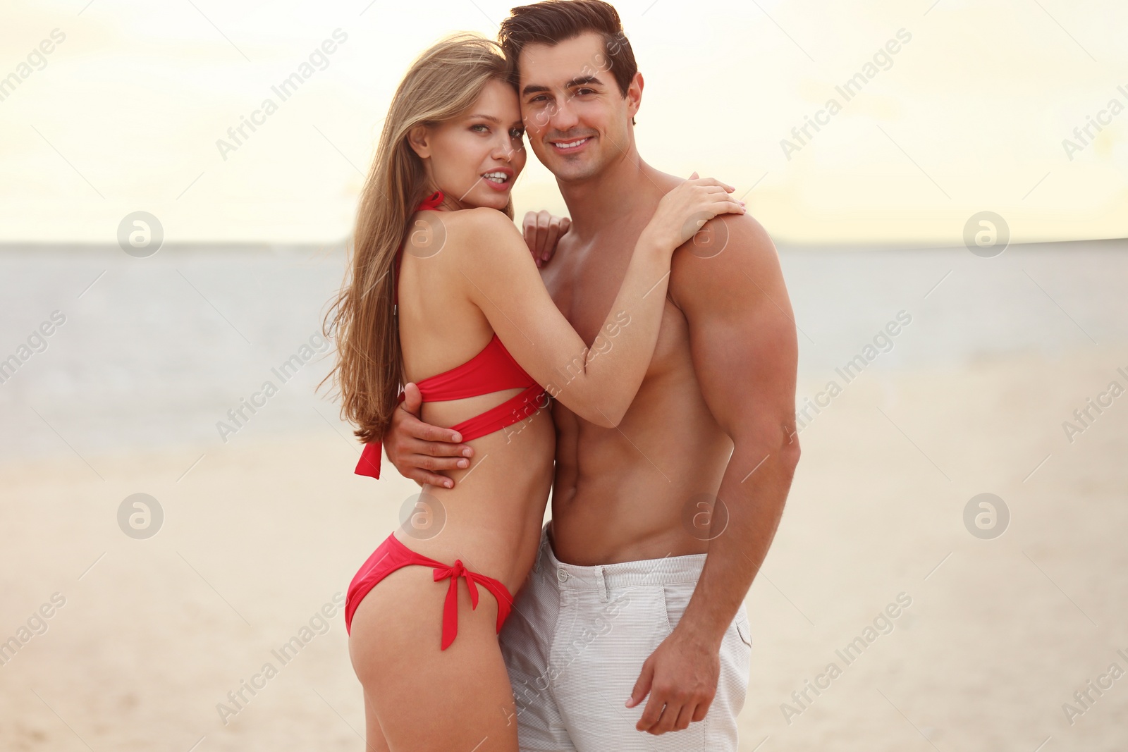 Photo of Happy young couple spending time together on sea beach at sunset