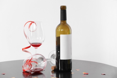 Photo of Glasses and bottle of wine on table against white background. After party chaos