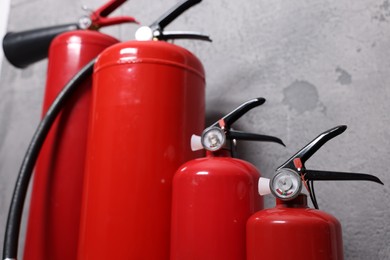 Photo of Red fire extinguishers near grey wall, selective focus