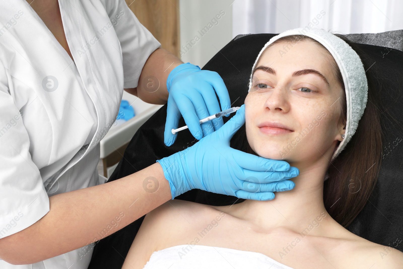 Photo of Cosmetologist giving facial injection to patient in clinic. Cosmetic surgery