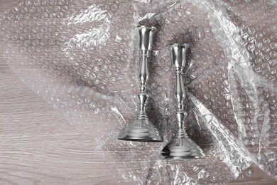 Candlesticks with bubble wrap on wooden table, flat lay