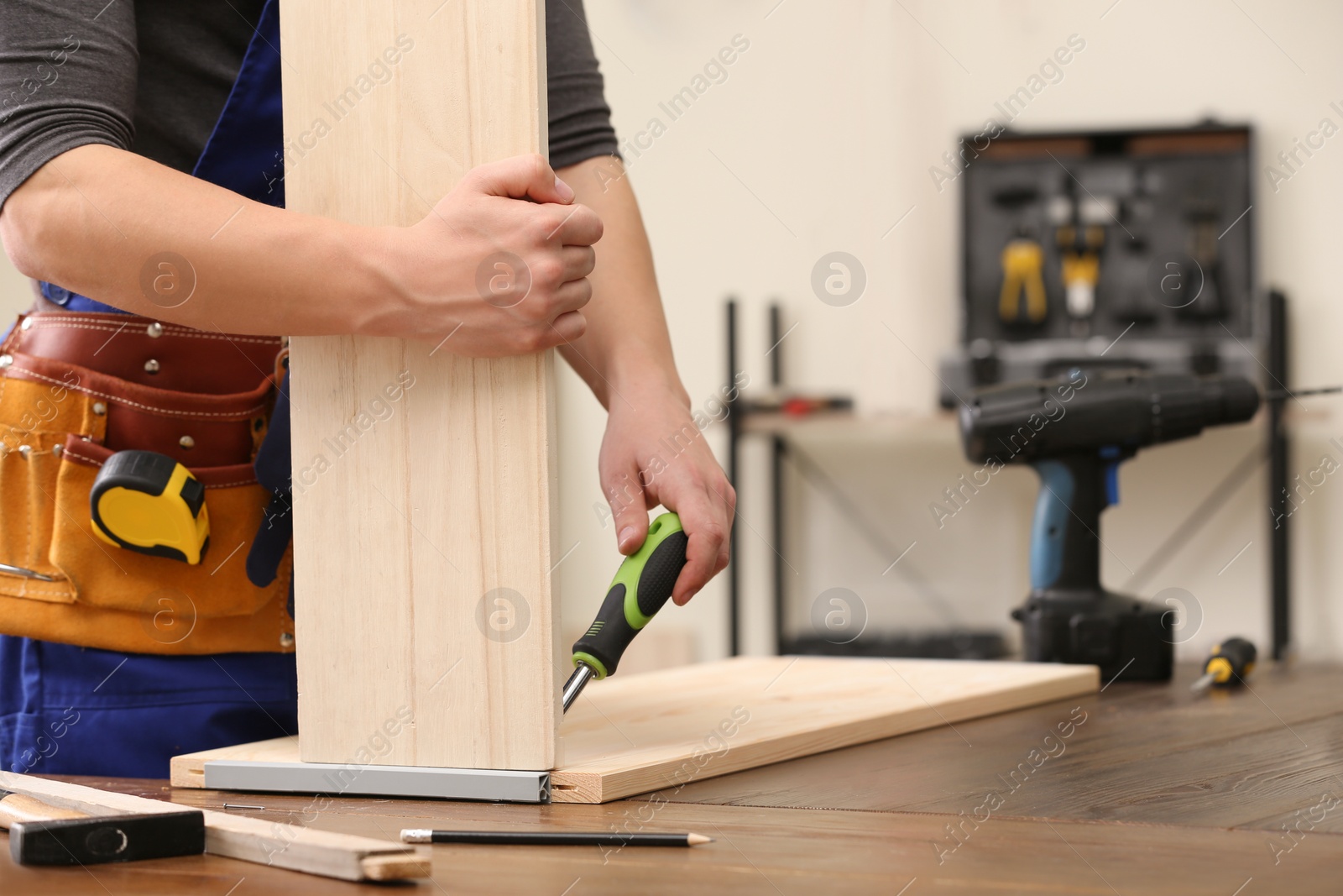 Photo of Young working man using screwdriver indoors, closeup with space for text. Home repair