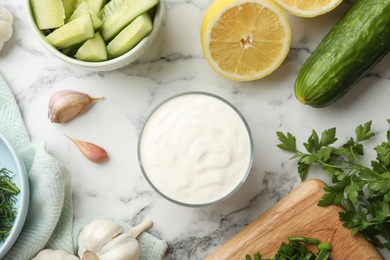 Photo of Flat lay composition with cucumber sauce and ingredients on marble background