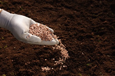 Photo of Man fertilizing soil, closeup. Space for text