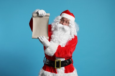 Photo of Merry Christmas. Santa Claus showing blank paper sheet on light blue background