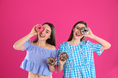 Photo of Beautiful young women with donuts on pink background