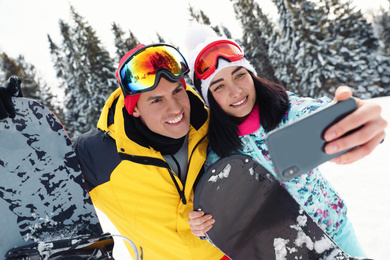 Photo of Couple taking selfie on snowy hill. Winter vacation