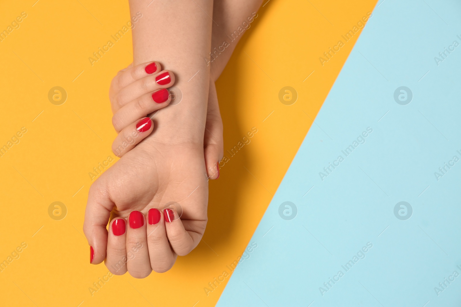 Photo of Woman showing red manicure on color background, top view with space for text. Nail polish trends