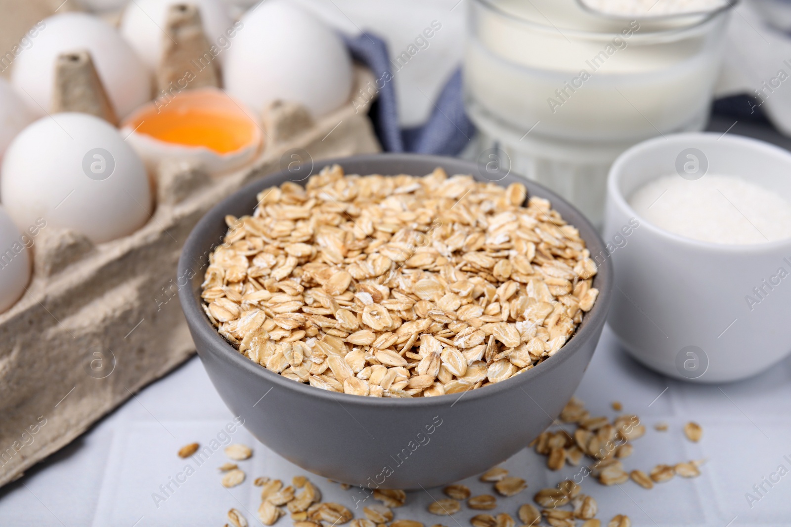 Photo of Different ingredients for cooking tasty oatmeal pancakes on white table, closeup