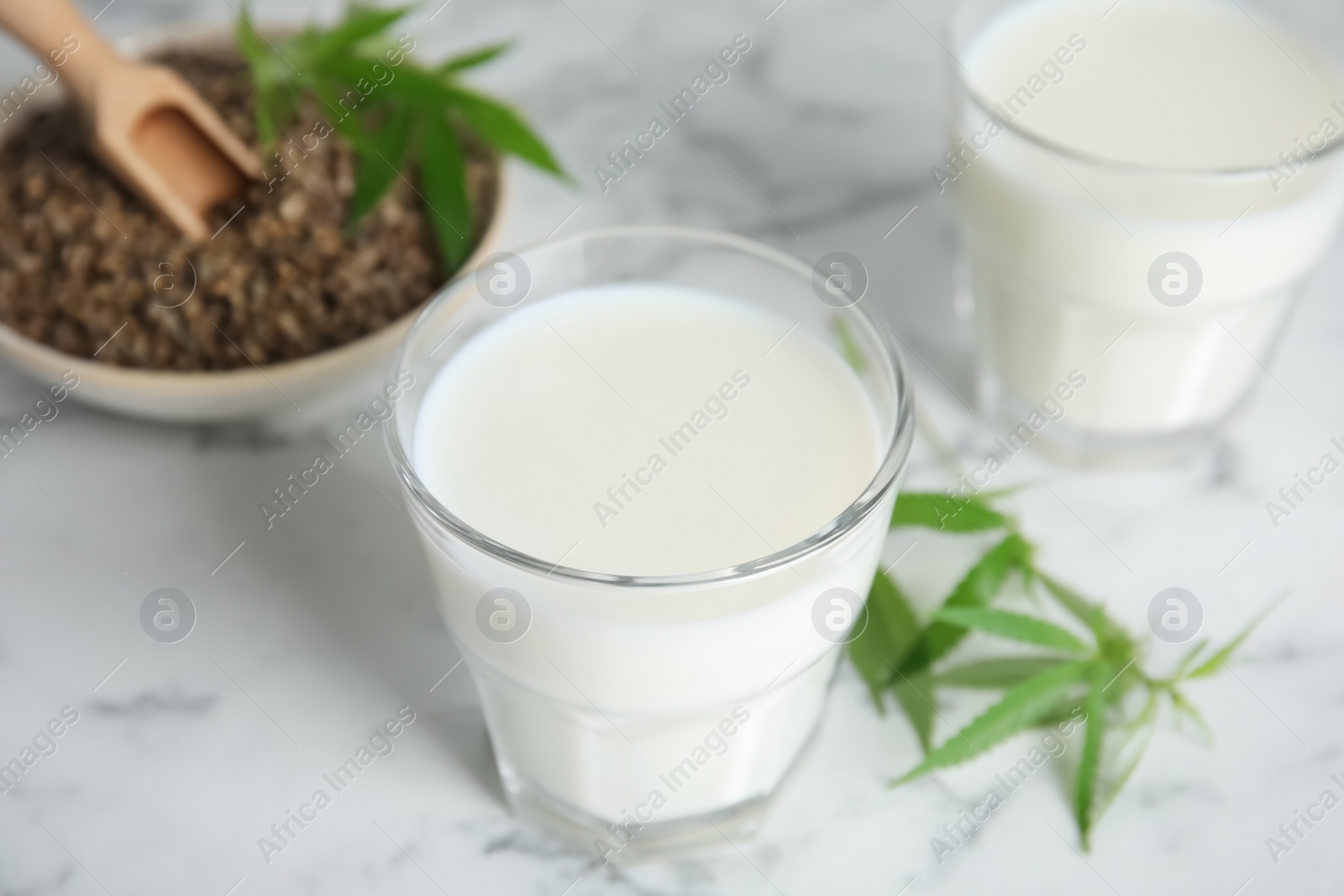 Photo of Hemp milk on white marble table, closeup