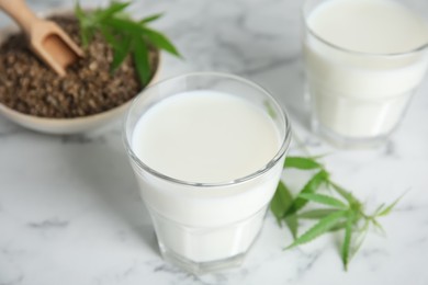Photo of Hemp milk on white marble table, closeup