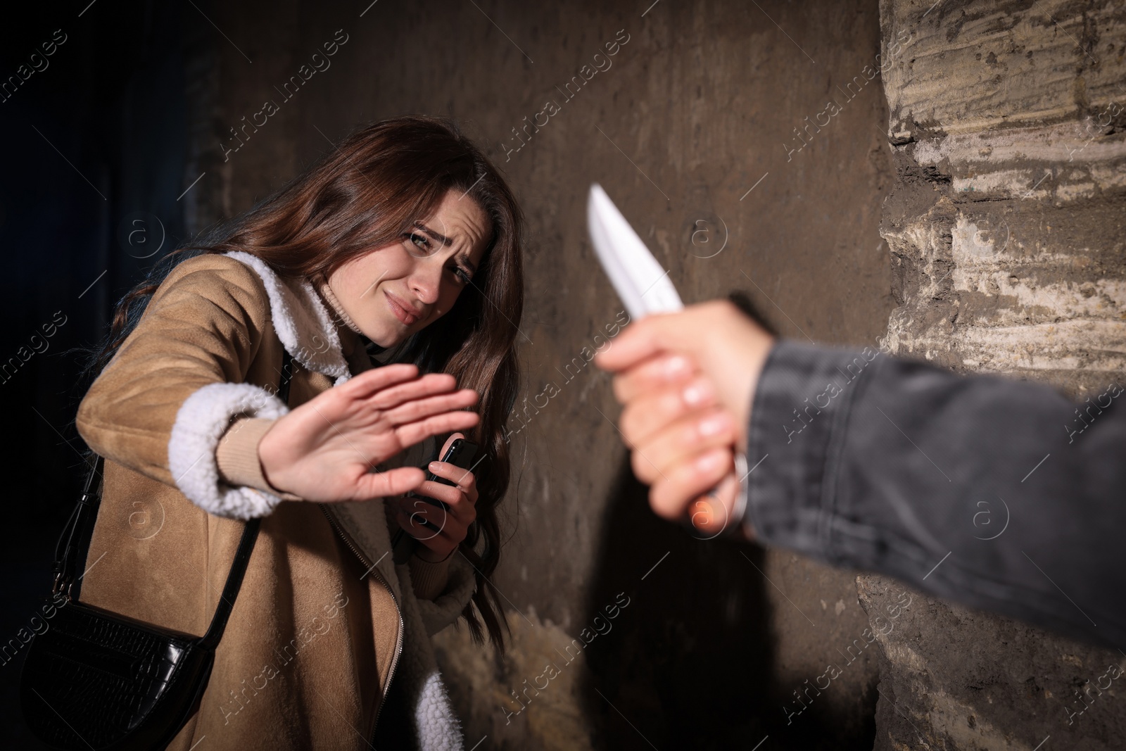 Photo of Criminal threatening young woman with knife at night. Self defense concept