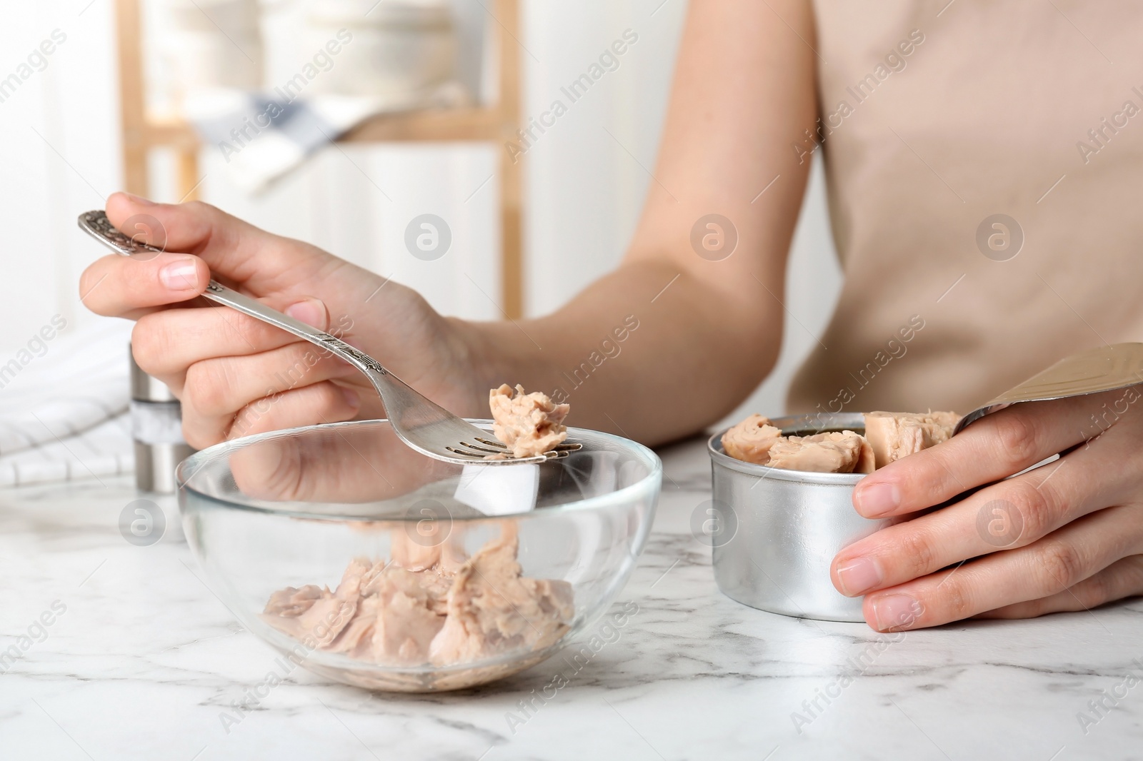 Photo of Woman with tin can of conserved tuna at table