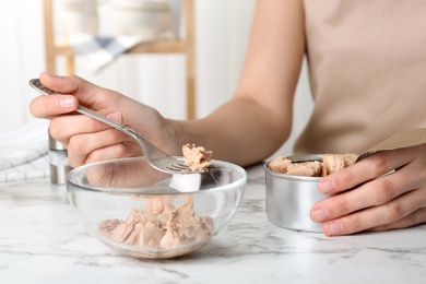 Woman with tin can of conserved tuna at table