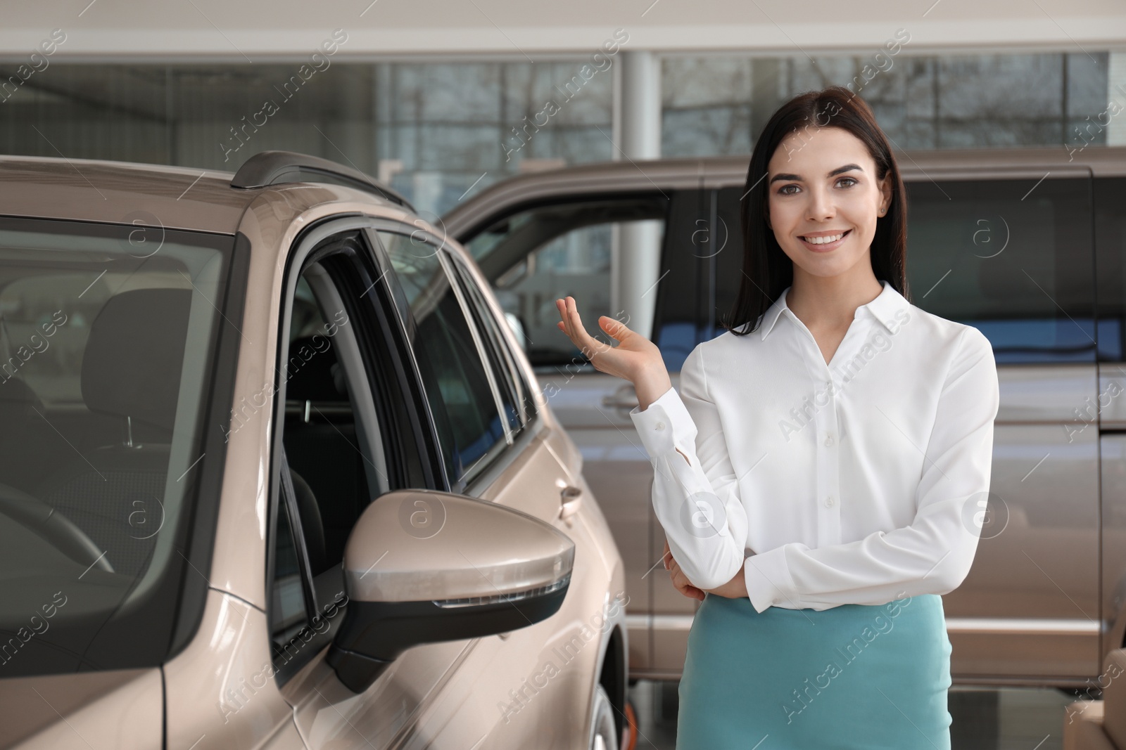 Photo of Young saleswoman near new car in dealership