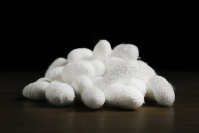 Photo of Heap of white silk cocoons on wooden table, closeup