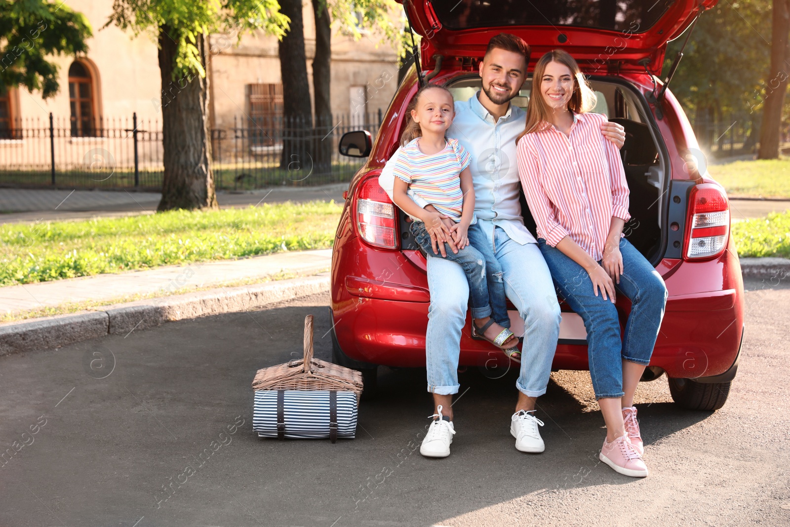 Photo of Happy family sitting in car's trunk outdoors