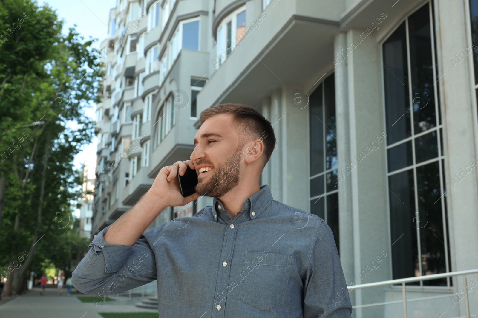 Photo of Young man talking on smartphone on city street