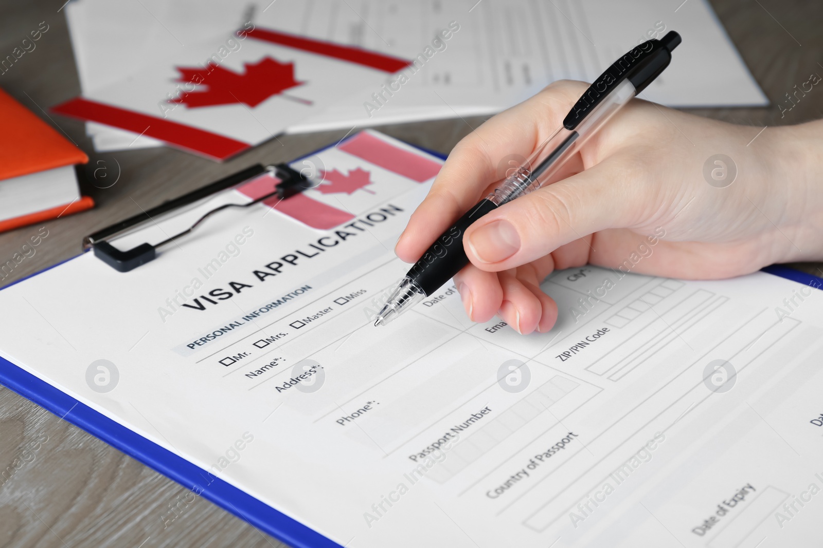 Photo of Woman filling visa application form to Canada at table, closeup