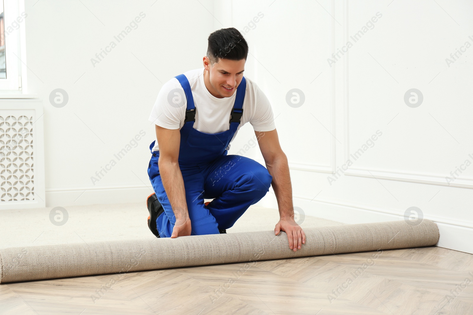 Photo of Worker rolling out new carpet in room