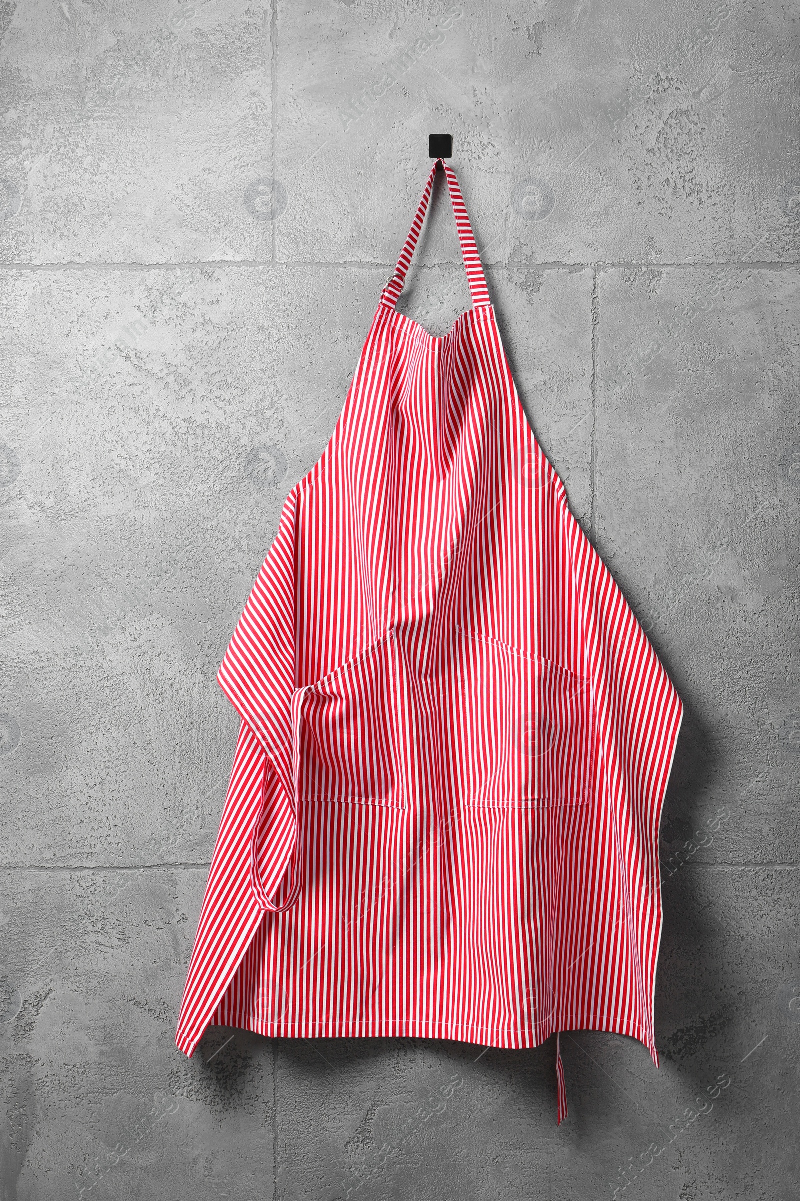 Photo of Clean red striped apron on grey tiled wall