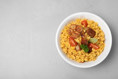 Photo of Bowl of delicious rice pilaf on grey background, top view with space for text