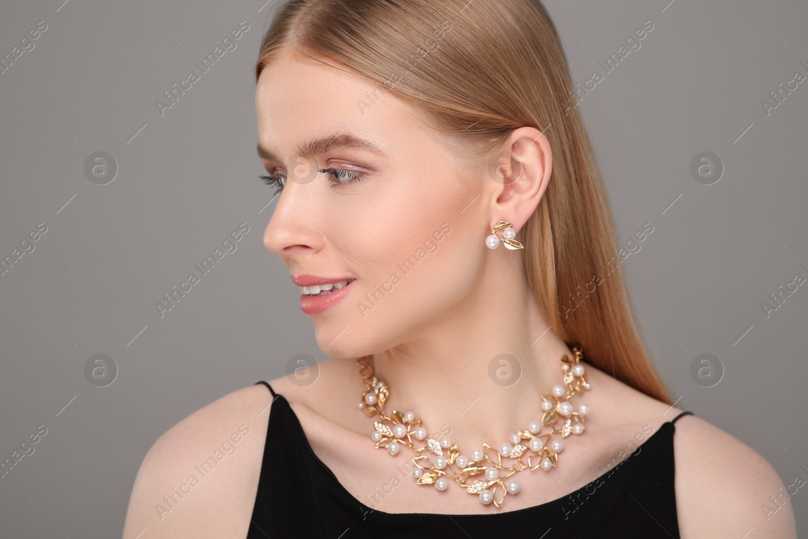 Photo of Beautiful young woman with elegant jewelry on gray background