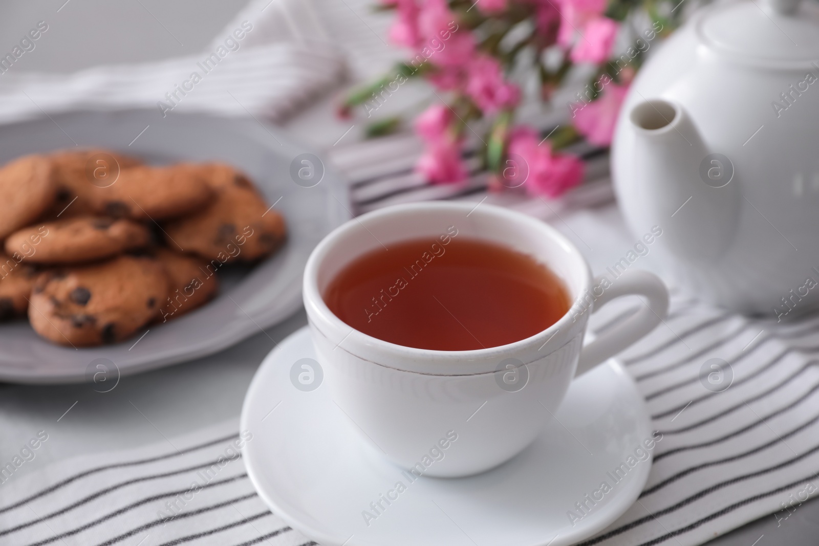 Photo of Cup of aromatic tea and tasty cookies on grey table