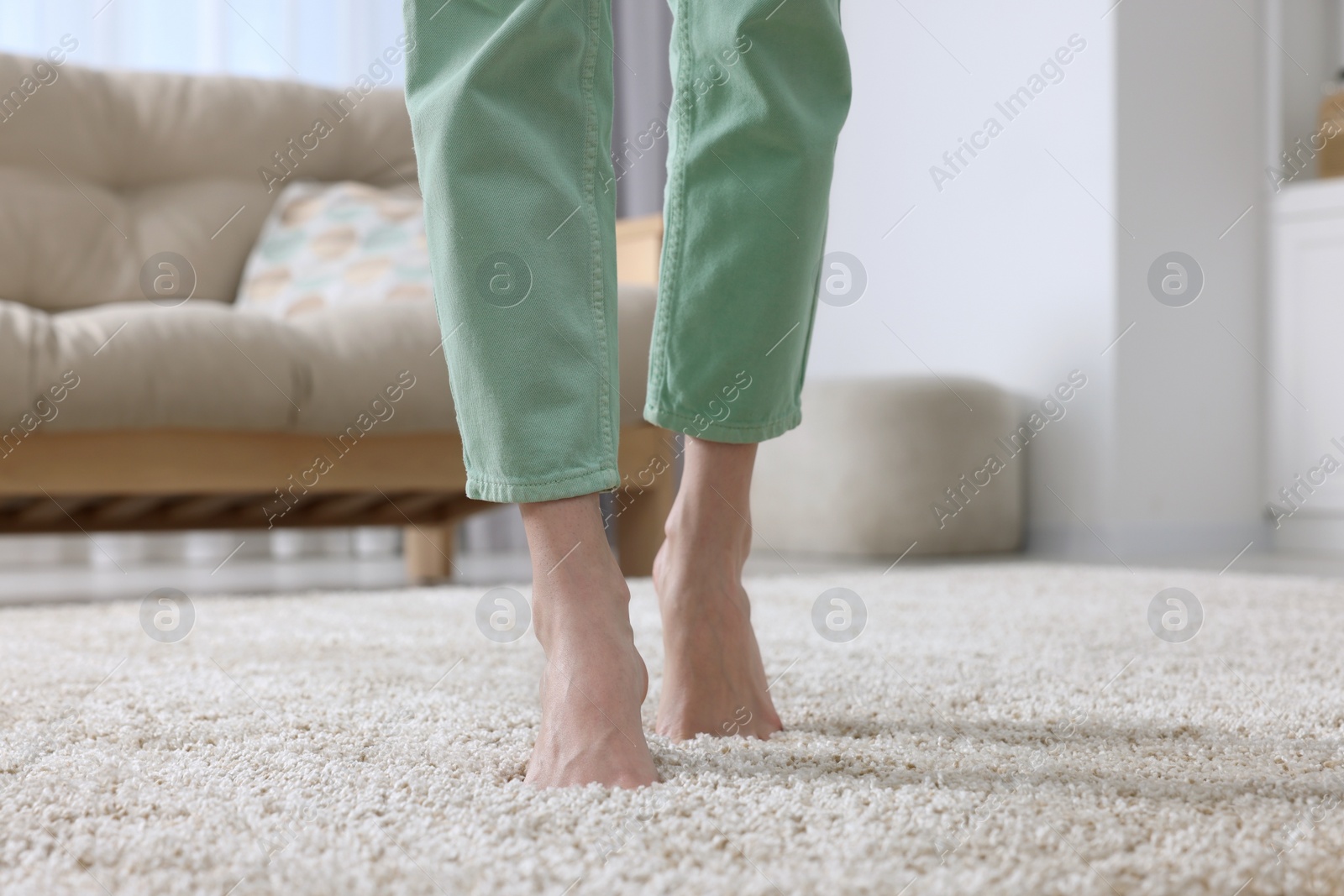 Photo of Woman walking on soft beige carpet at home, closeup