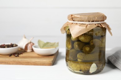Photo of Tasty pickled cucumbers in jar and ingredients on white table. Space for text