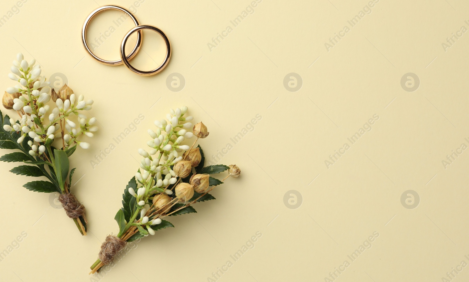 Photo of Small stylish boutonnieres and rings on beige background, flat lay. Space for text