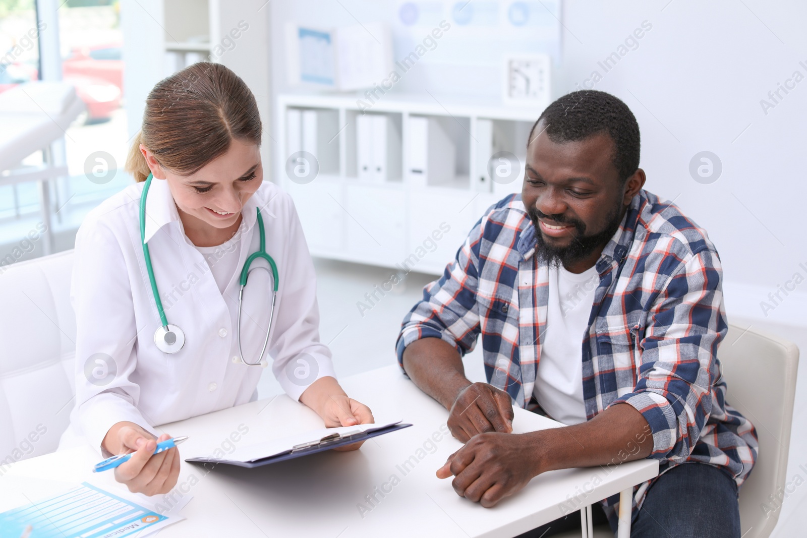 Photo of Young doctor speaking to African-American patient in hospital