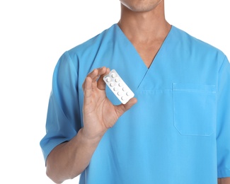Male doctor holding pills on white background, closeup. Medical object