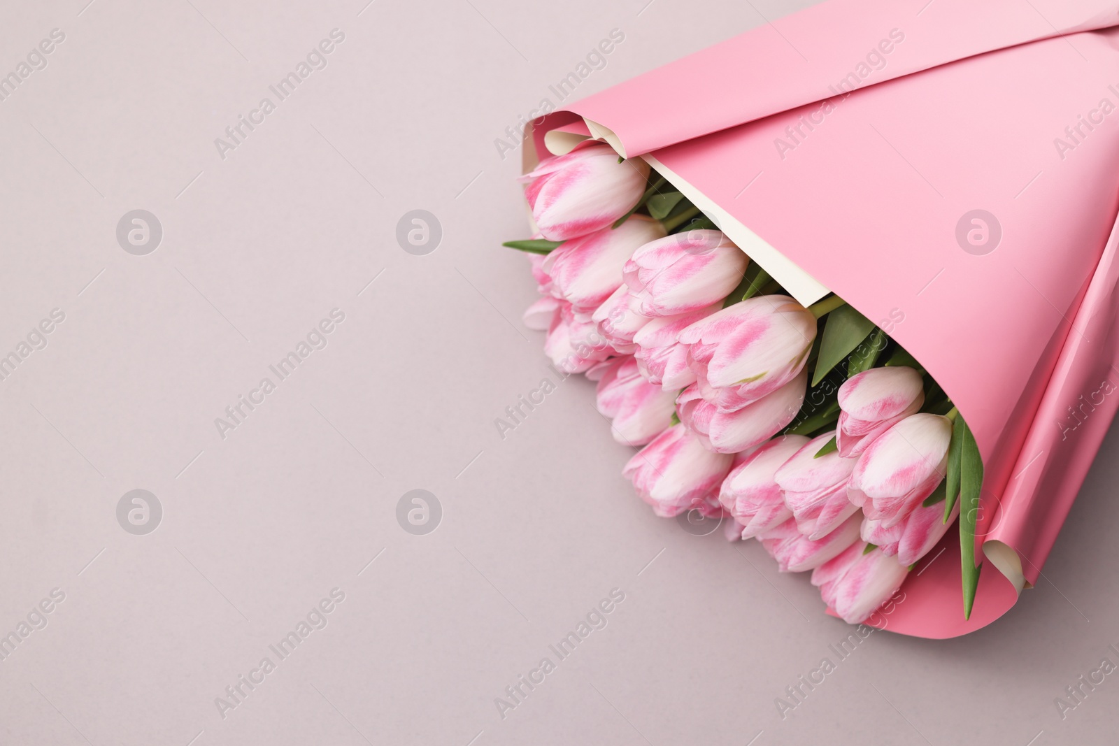 Photo of Beautiful bouquet of fresh pink tulips on light background, top view. Space for text