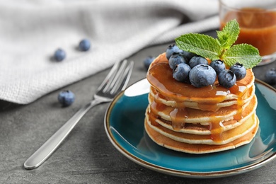 Photo of Delicious pancakes with fresh blueberries and syrup on grey table