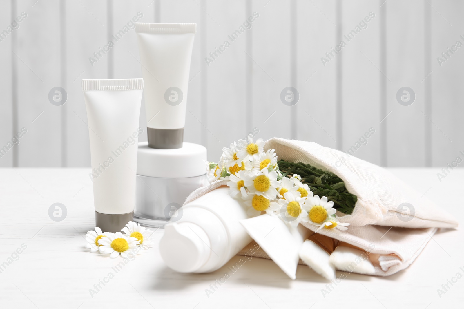 Photo of Set of different cosmetic products and chamomile flowers on white table