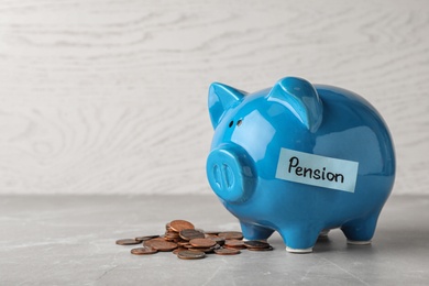 Piggy bank with word PENSION and coins on table. Space for text