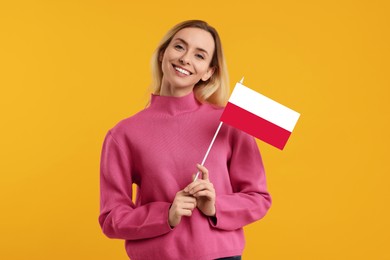 Happy young woman with flag of Poland on yellow background