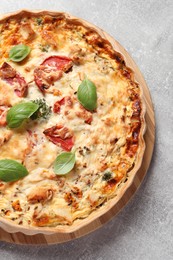 Photo of Tasty quiche with tomatoes, basil and cheese served on light table, top view