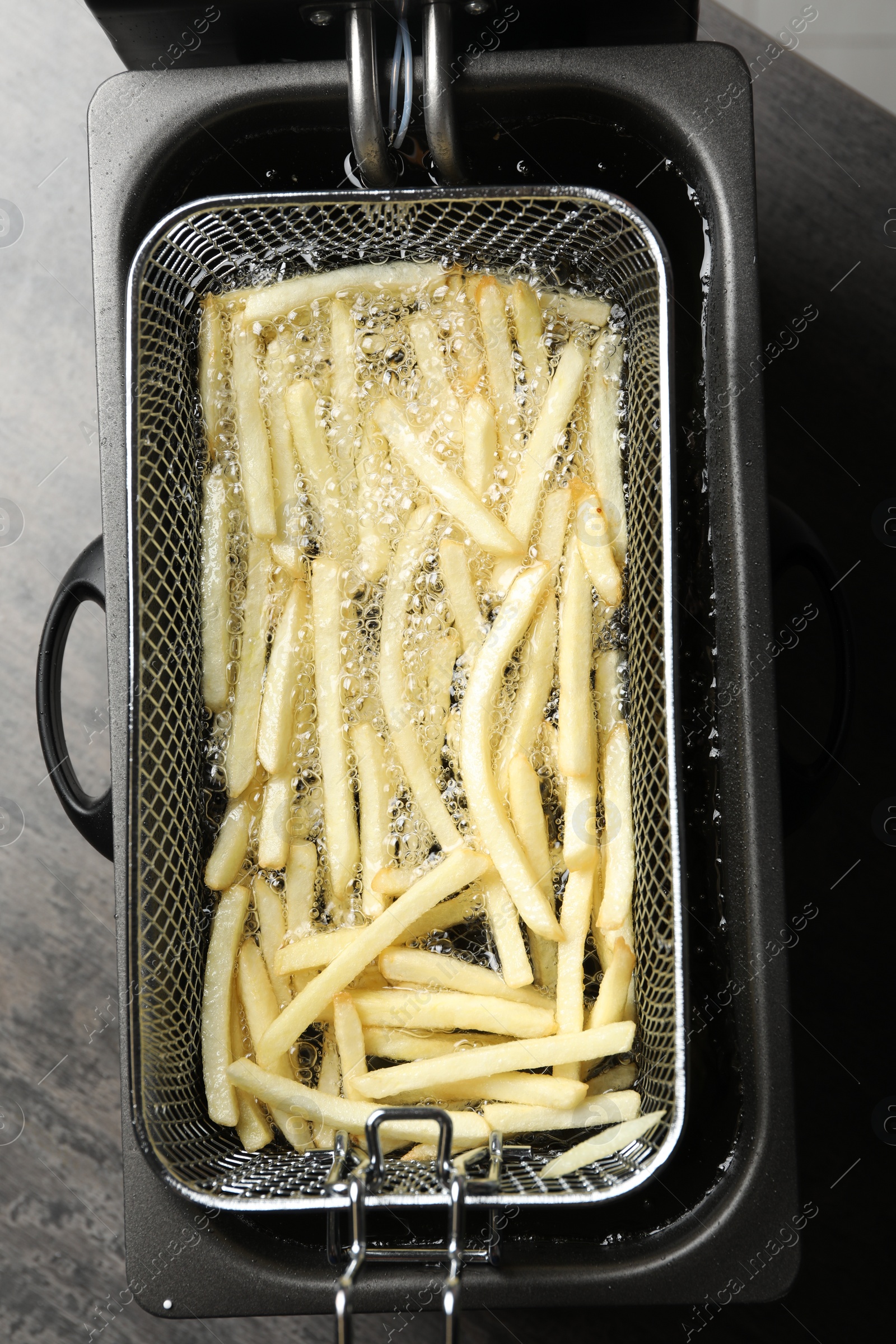 Photo of Cooking delicious french fries in hot oil, top view