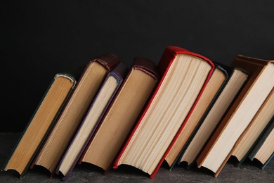 Photo of Stack of hardcover books on grey stone table against black background