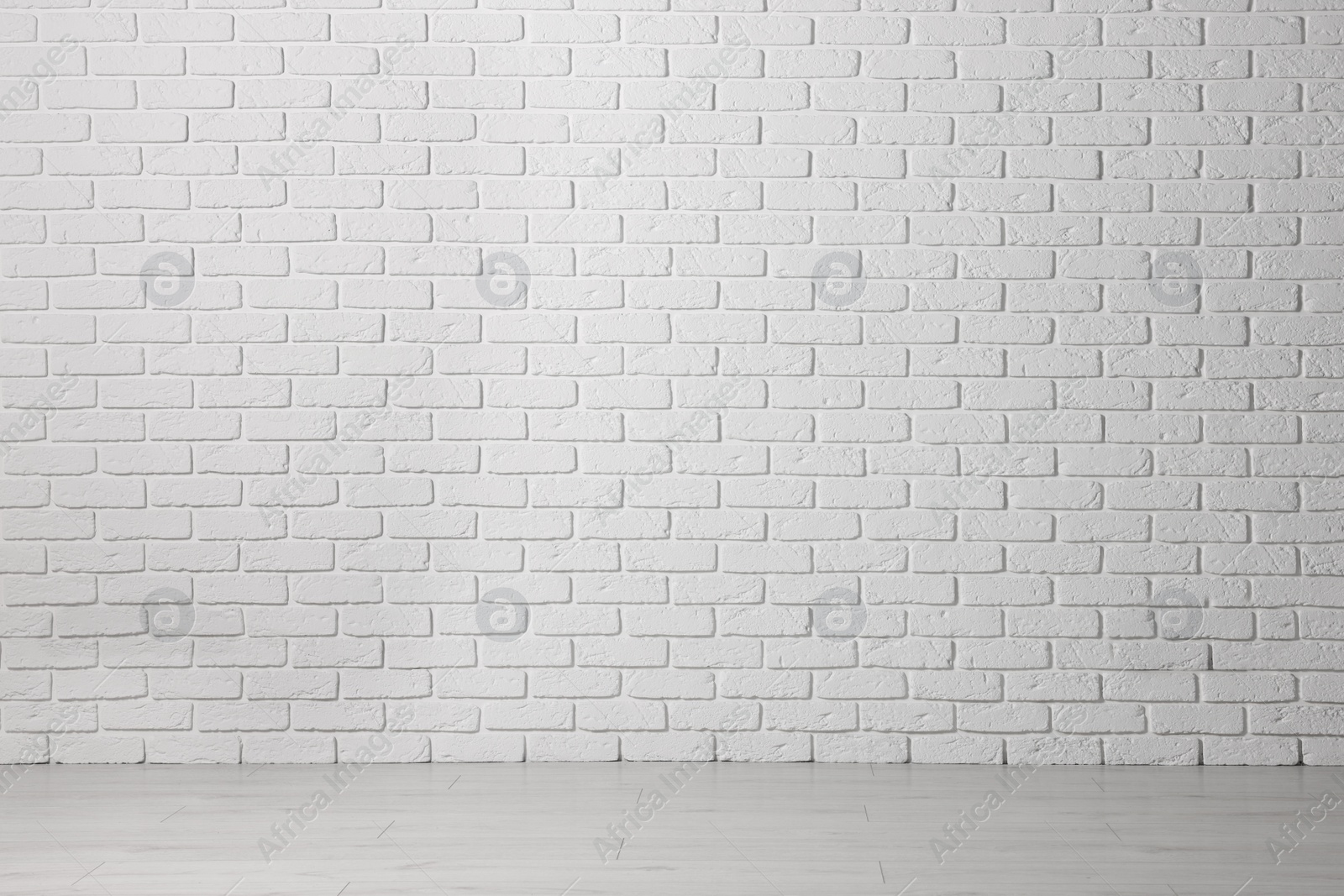 Photo of Beautiful white brick wall and wooden floor in clean empty room