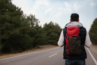 Photo of Man with backpack on road near forest, back view