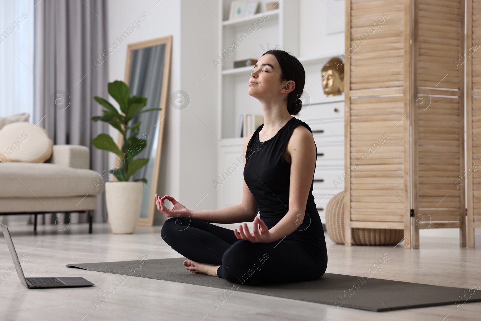 Photo of Beautiful girl having yoga class with online couch at home