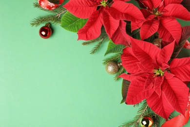 Photo of Flat lay composition with poinsettias (traditional Christmas flowers) and holiday decor on green background. Space for text