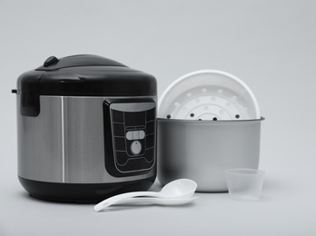 Photo of Modern electric multi cooker, parts and accessories on grey background
