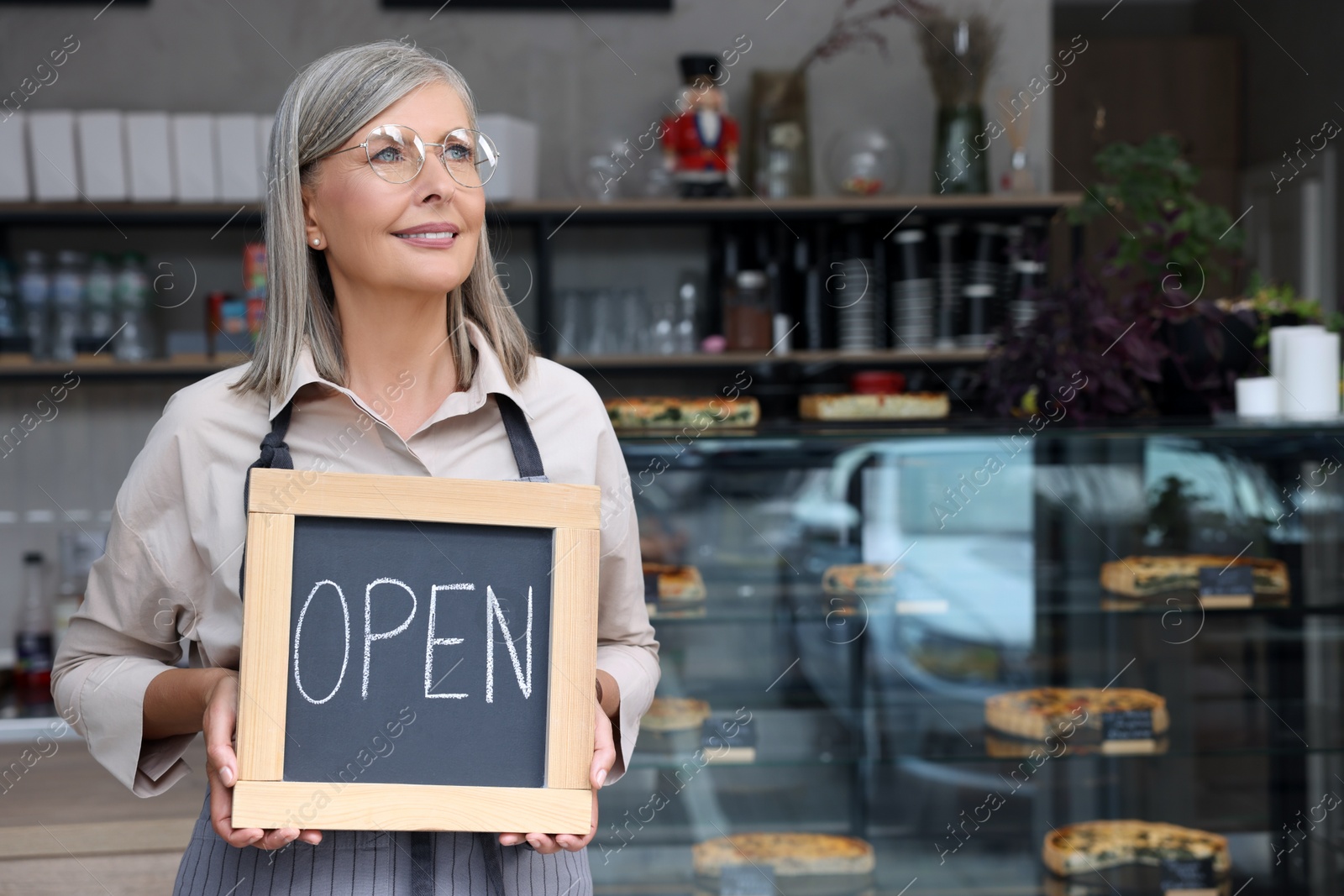 Photo of Happy business owner holding open sign in her cafe, space for text