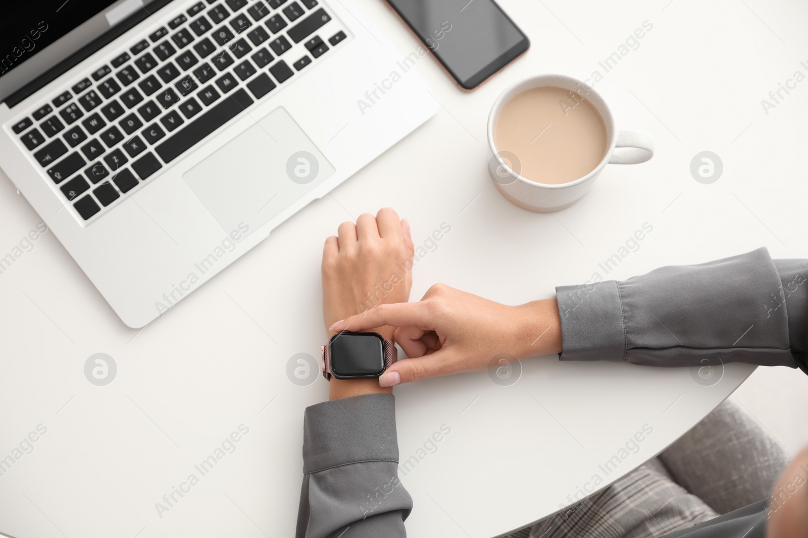 Image of Woman checking stylish smart watch at table, top view