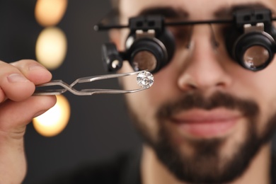 Male jeweler evaluating gemstone in workshop, closeup