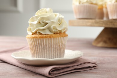 Tasty cupcake with vanilla cream on pink wooden table, closeup